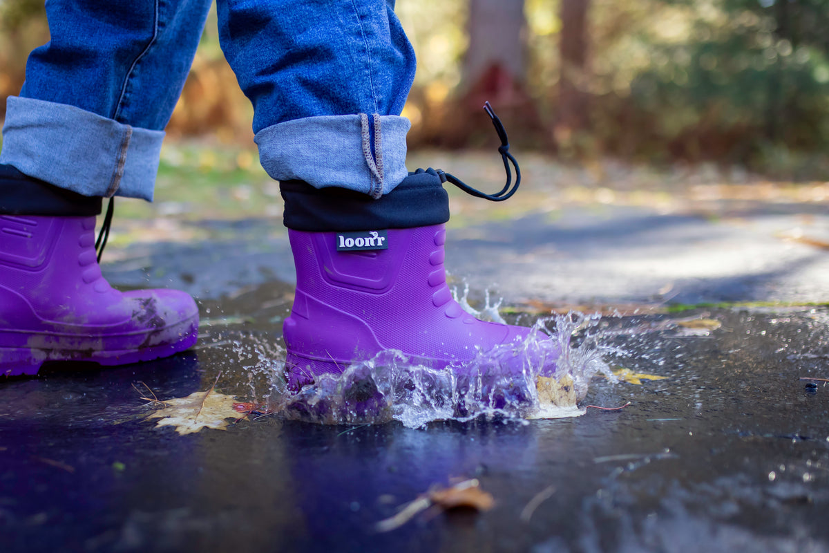 A purple Loon'r boot splashing through a puddle